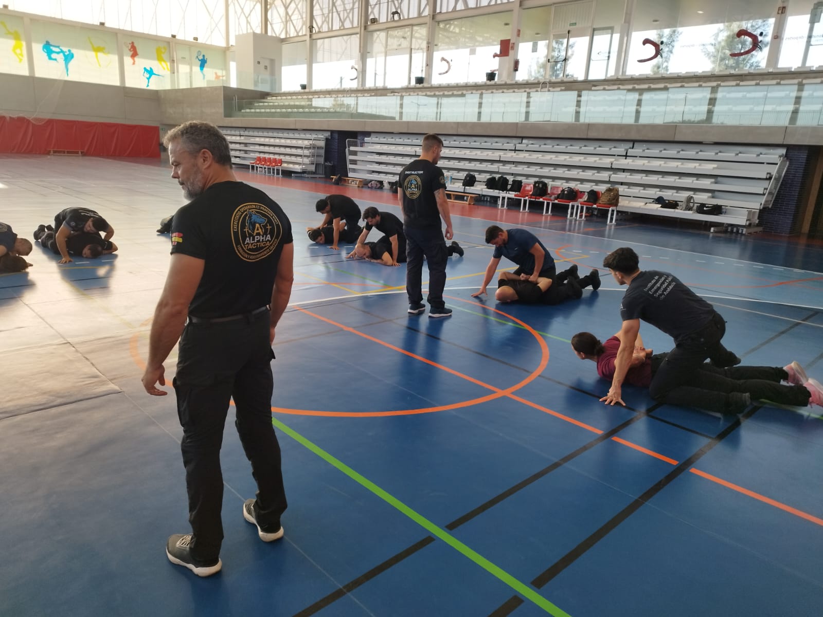 Instructores de Alpha Táctica supervisando las prácticas de defensa policial en el pabellón deportivo